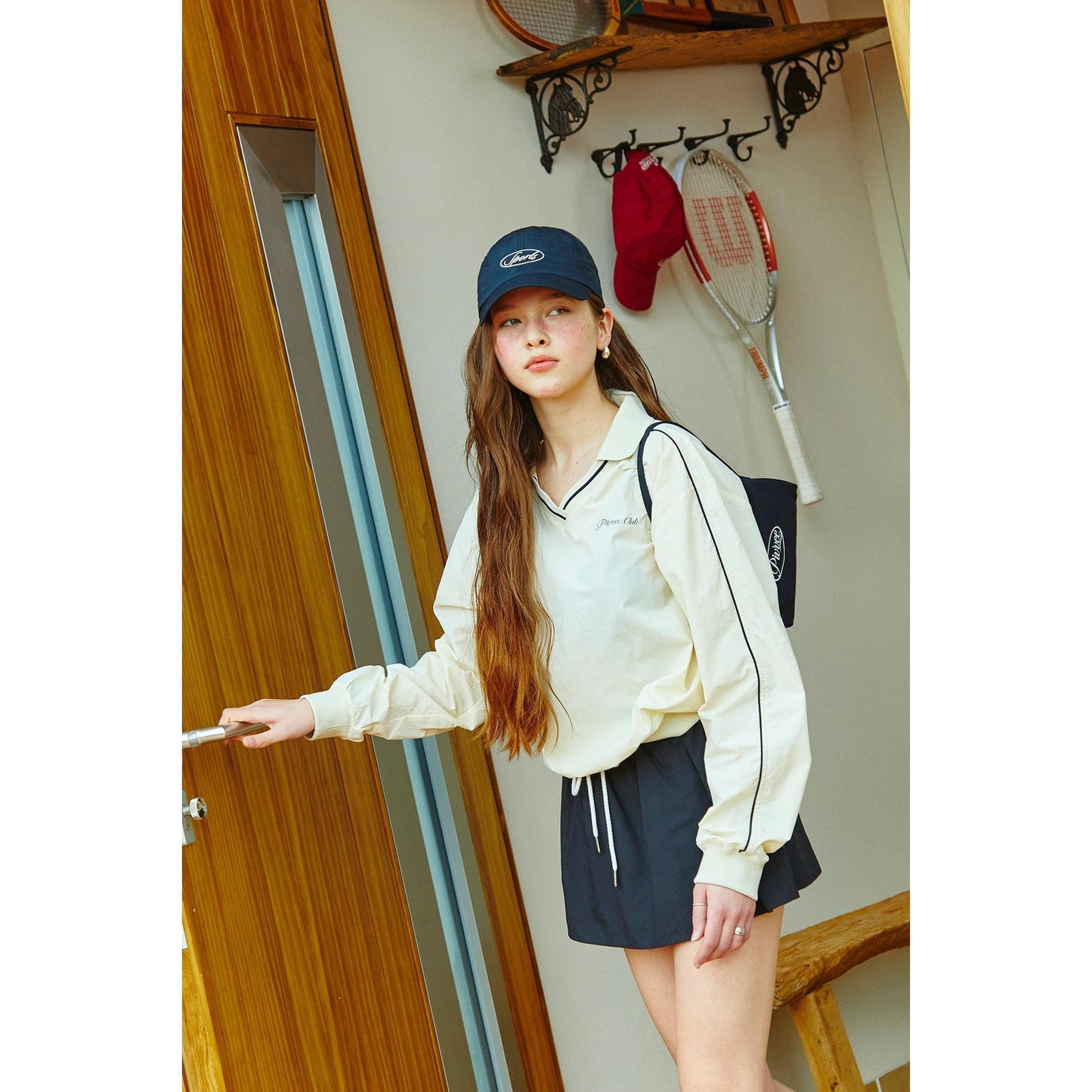 model wearing piv'vee club piste top in cream with sporty design, paired with shorts and accessories