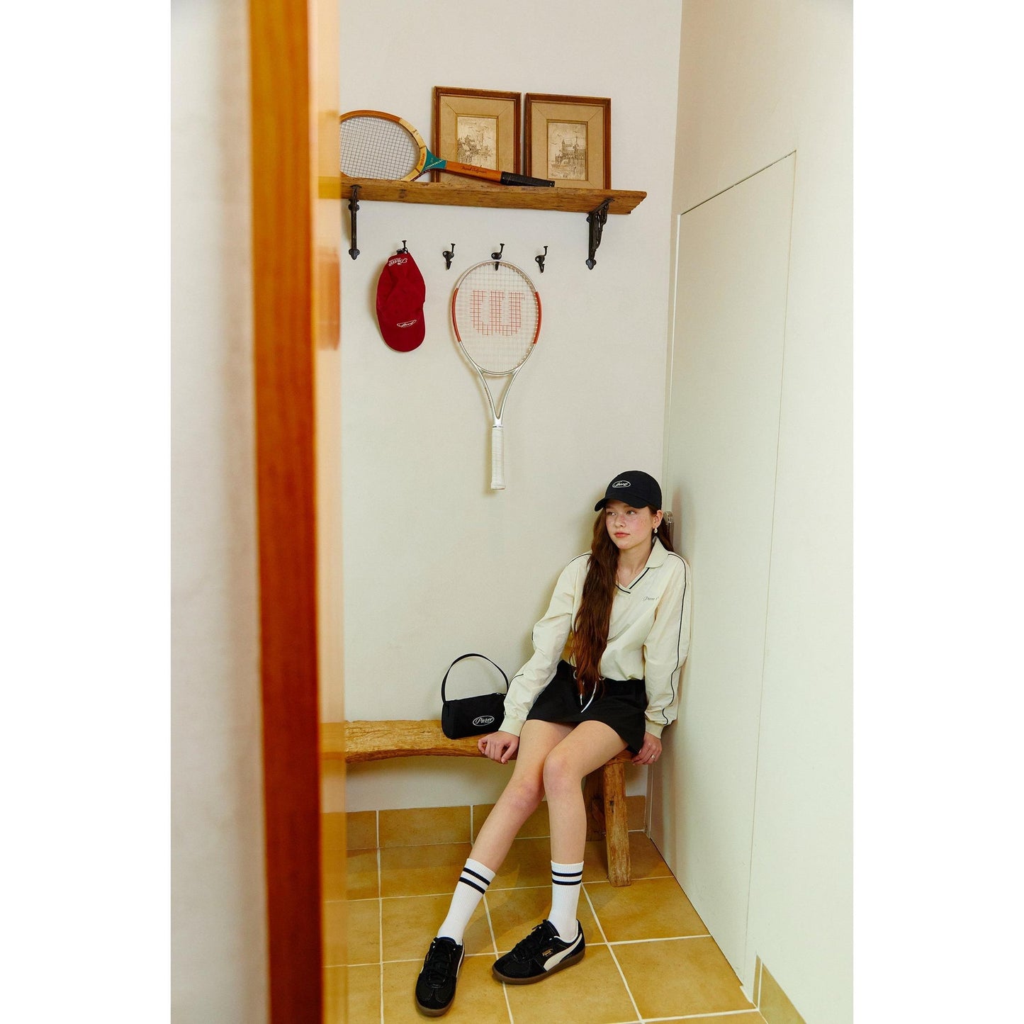 piv'vee club piste top in cream paired with a stylish skirt in a trendy indoor sports setting