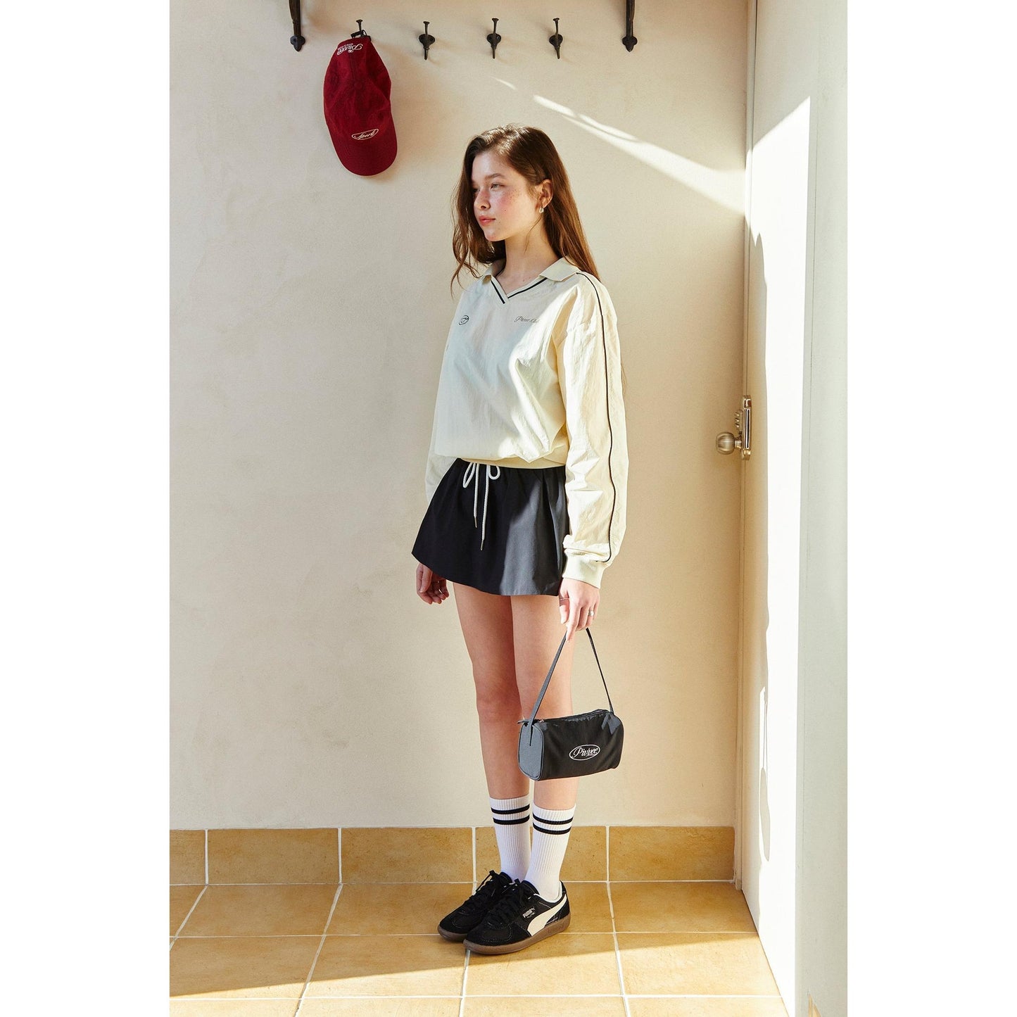 piv'vee club piste top in light yellow with long sleeves, styled with a black skirt and accessories